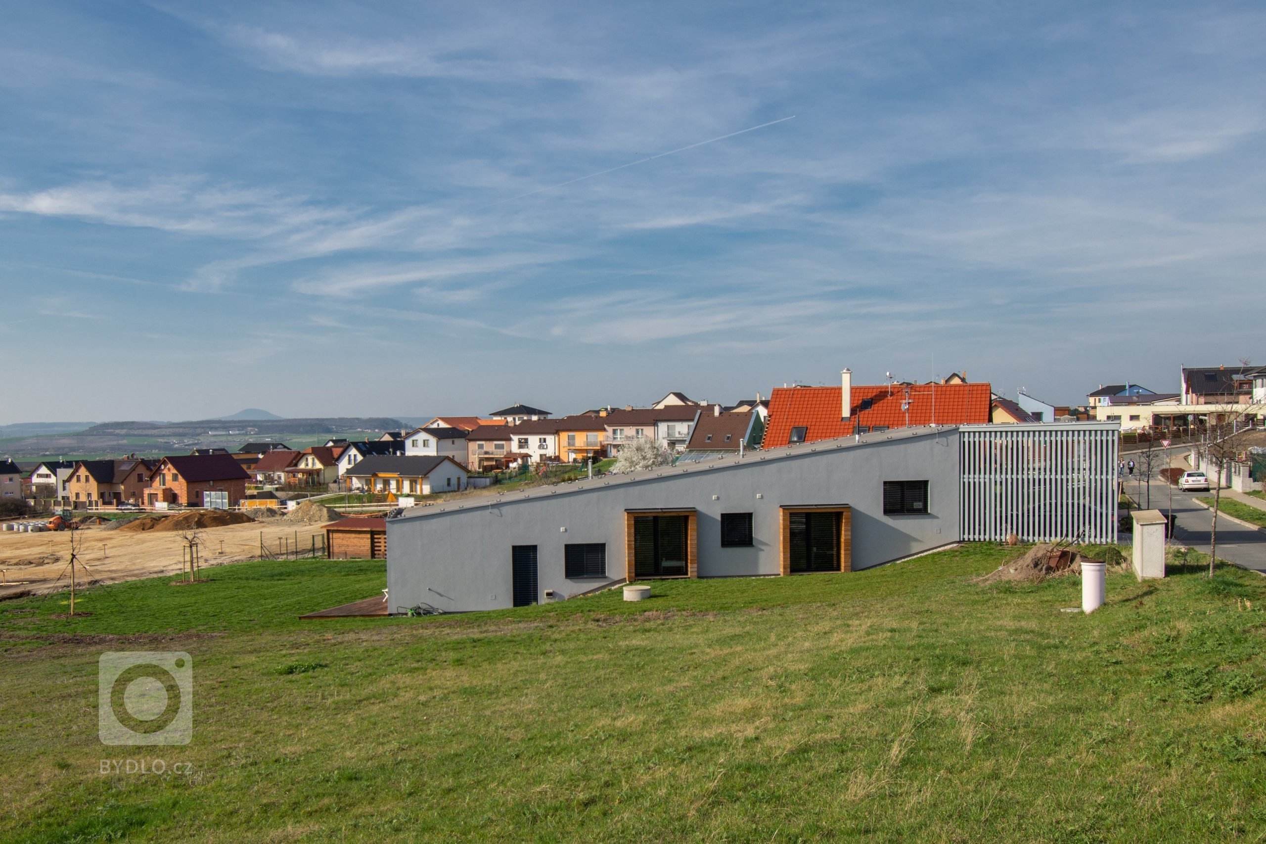 Klienty byla mladá rodina s nízkým rozpočtem a hlavním bodem zadání byl bungalov s výhledem na severozápad na České středohoří. Dům měl reagovat na terén…