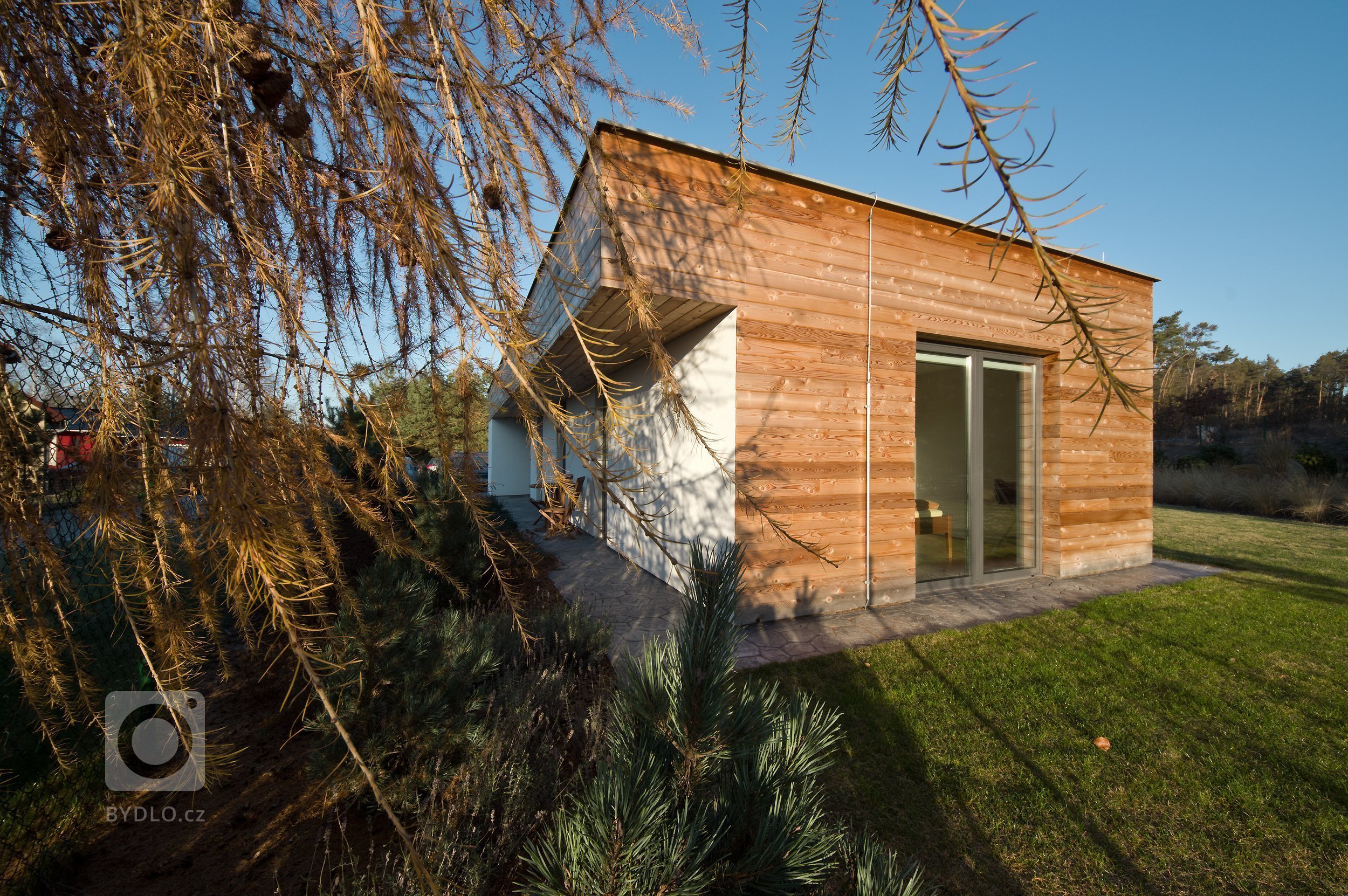 Pozemek pro tento dům můžeme najít v&nbsp;řídce zastavěné periferní části města. Na jedné straně parcely se nachází borovicový les, který dodává atmosféru…