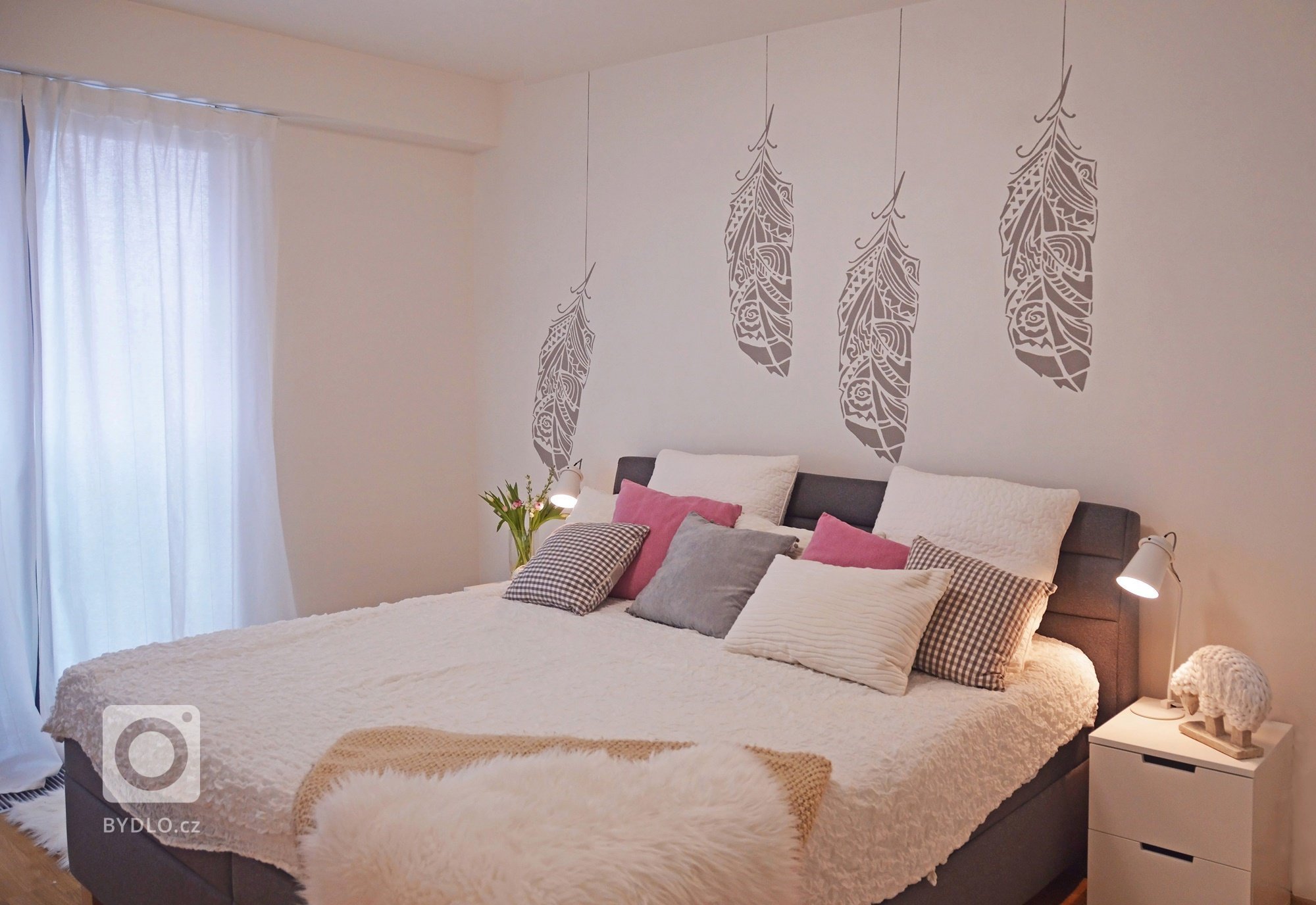 Visící pírka na stěně namalovaní z šablon.