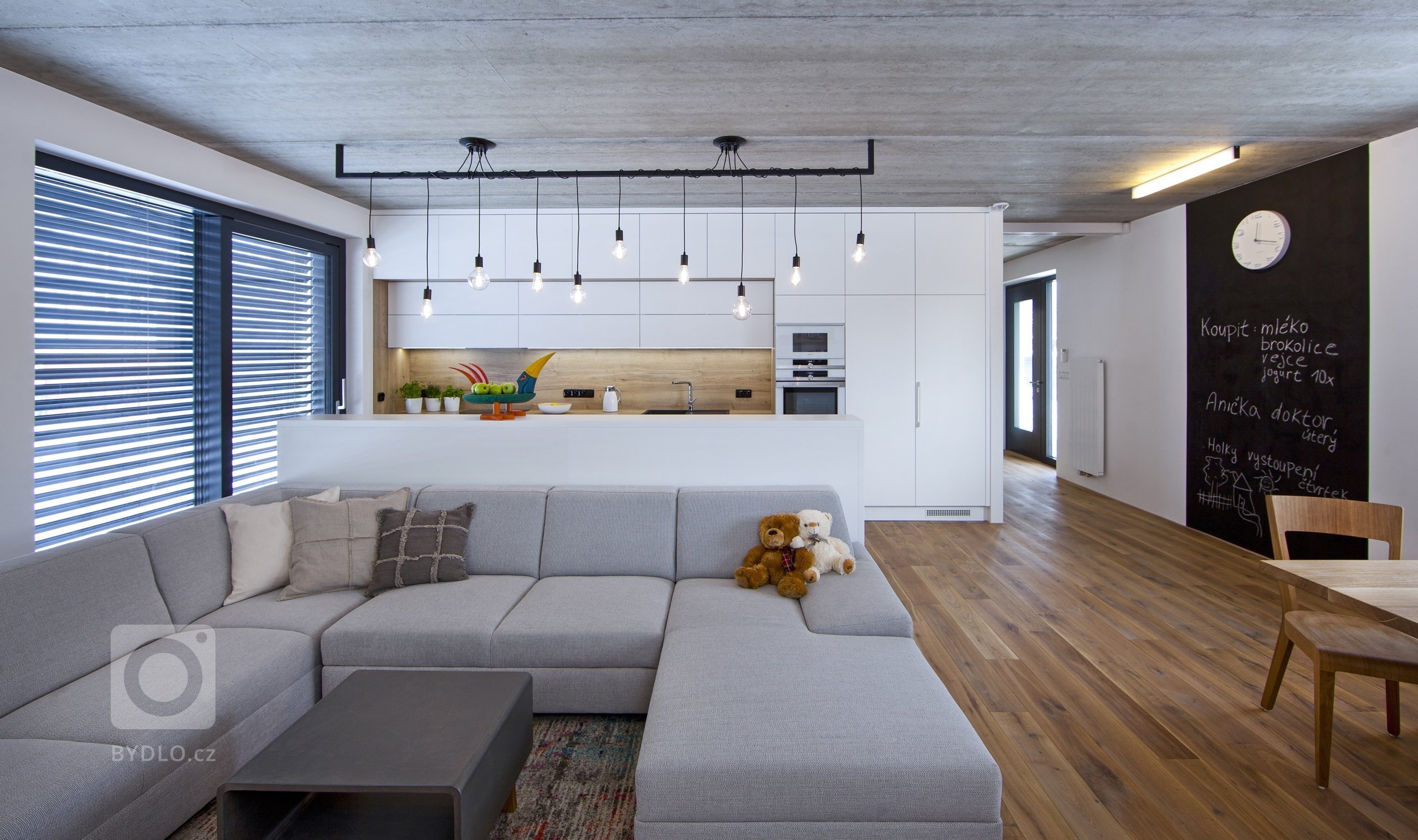 V celém domě se prolínají přírodní materiály s černými kovovými prvky a detaily s bílými stěnami a dveřmi. Industriální ráz podtrhují přiznané betonové stropy…