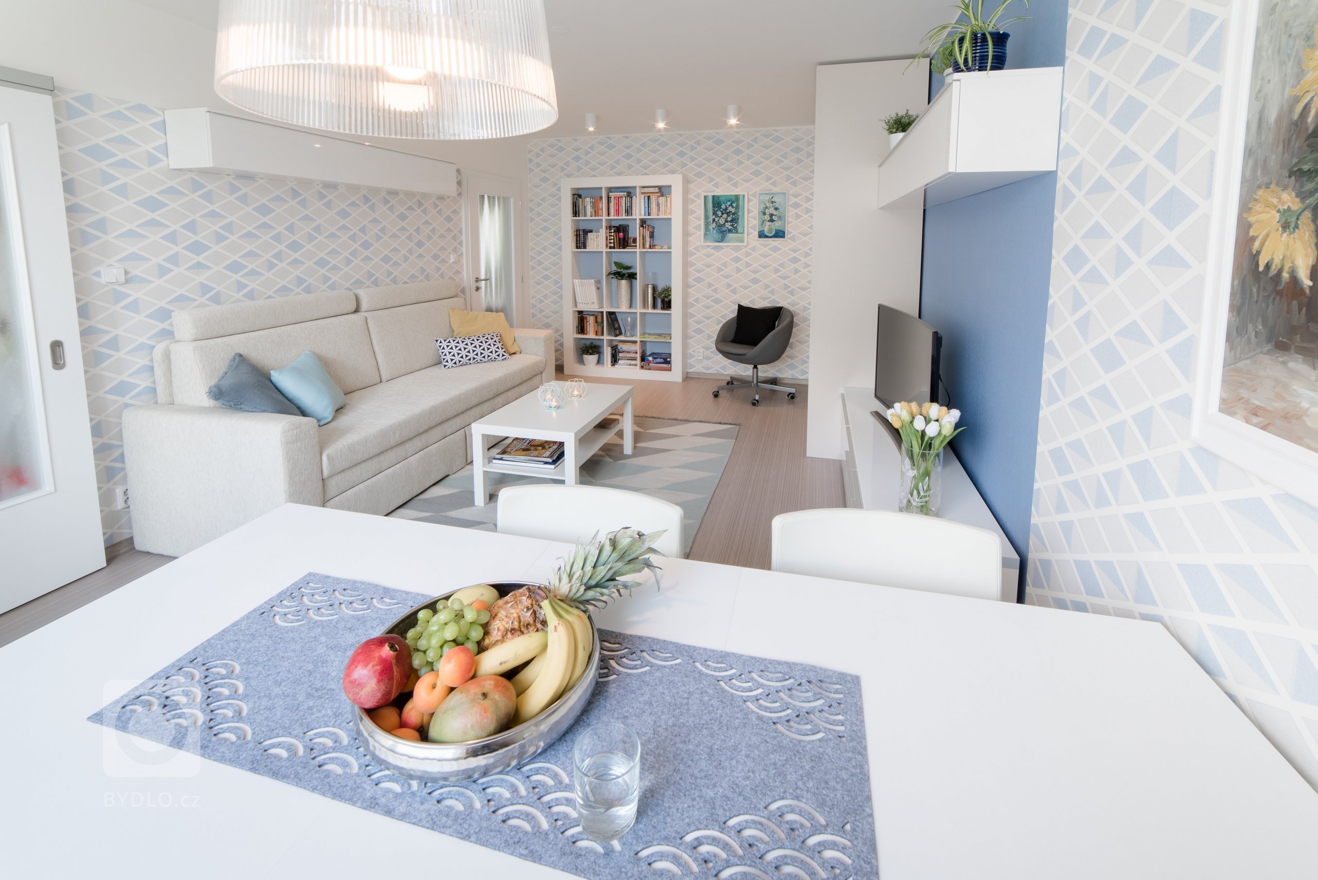 Původní velmi tmavý obývací pokoj se novým bílo-modro-béžovým laděním proměnil v příjemně světlý, svěží prostor. Výrazné tapety a koberec s pastelovými vzory…