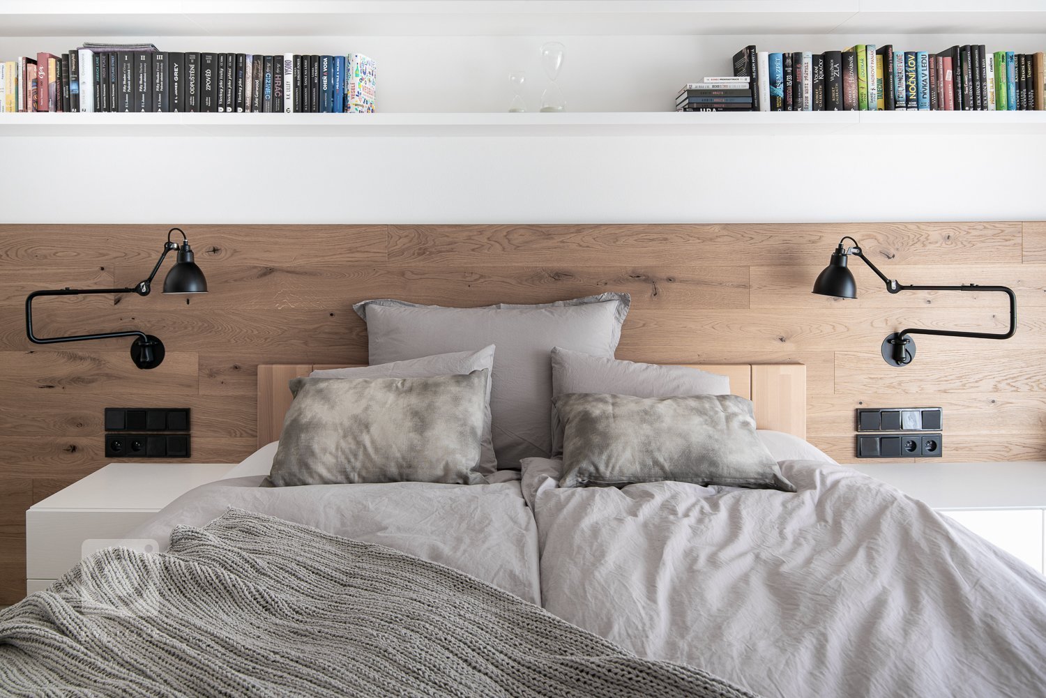 Pokud hovoříme o čistých liniích, tak nemůžeme opomenout ani dlouhou polici na knihy, čtecí lampičky a výrazné černé osvětlení nad postelí.