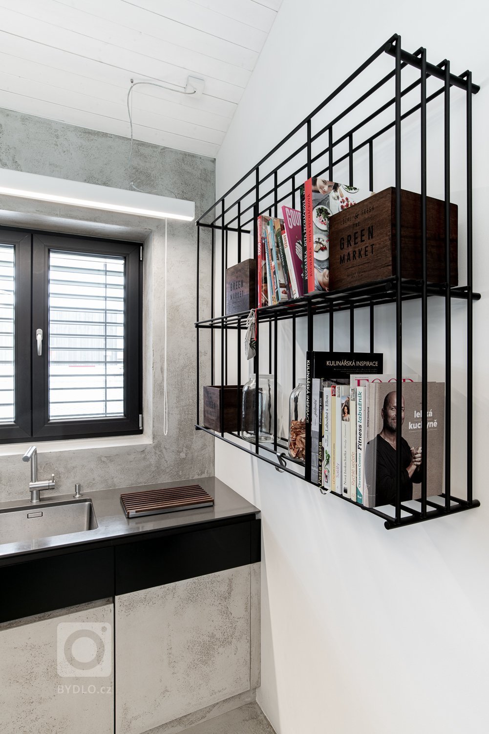 Černá ocelová konstrukce je doplněna o stolovou desku z ořechu. Židle oblého tvaru barevně korespondují se stolem.