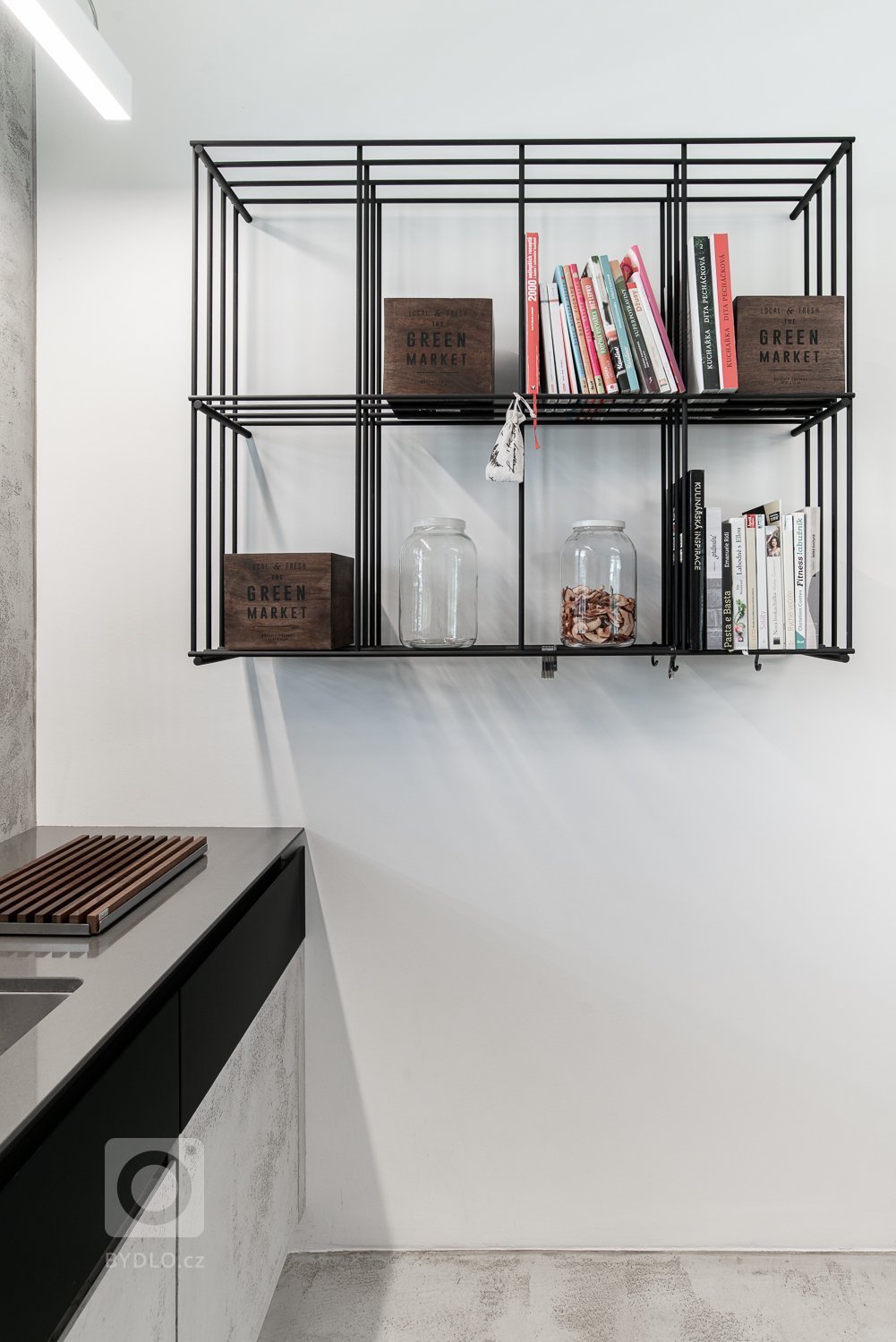 Černá ocelová konstrukce je doplněna o stolovou desku z ořechu. Židle oblého tvaru barevně korespondují se stolem.