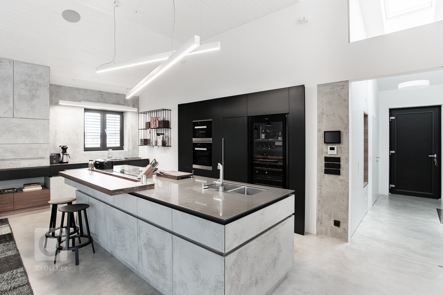 Velkým plochám dominuje bílá barva na stěnách, stropu a podlaze. Dále pak světle šedá betonová stěrka na nábytku.