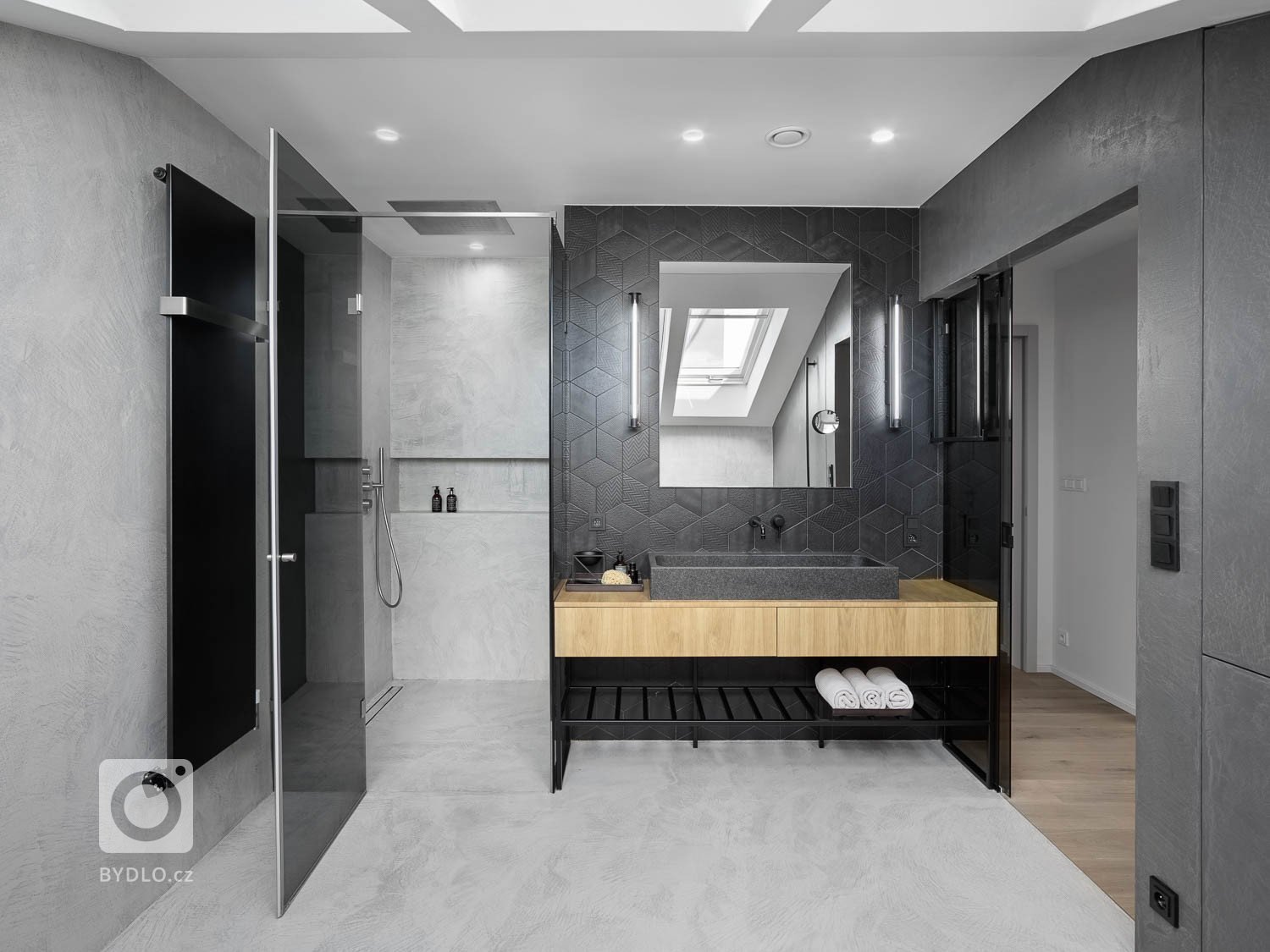 koupelně dominuje šedá betonová stěrka a keramický obklad se vzorem.