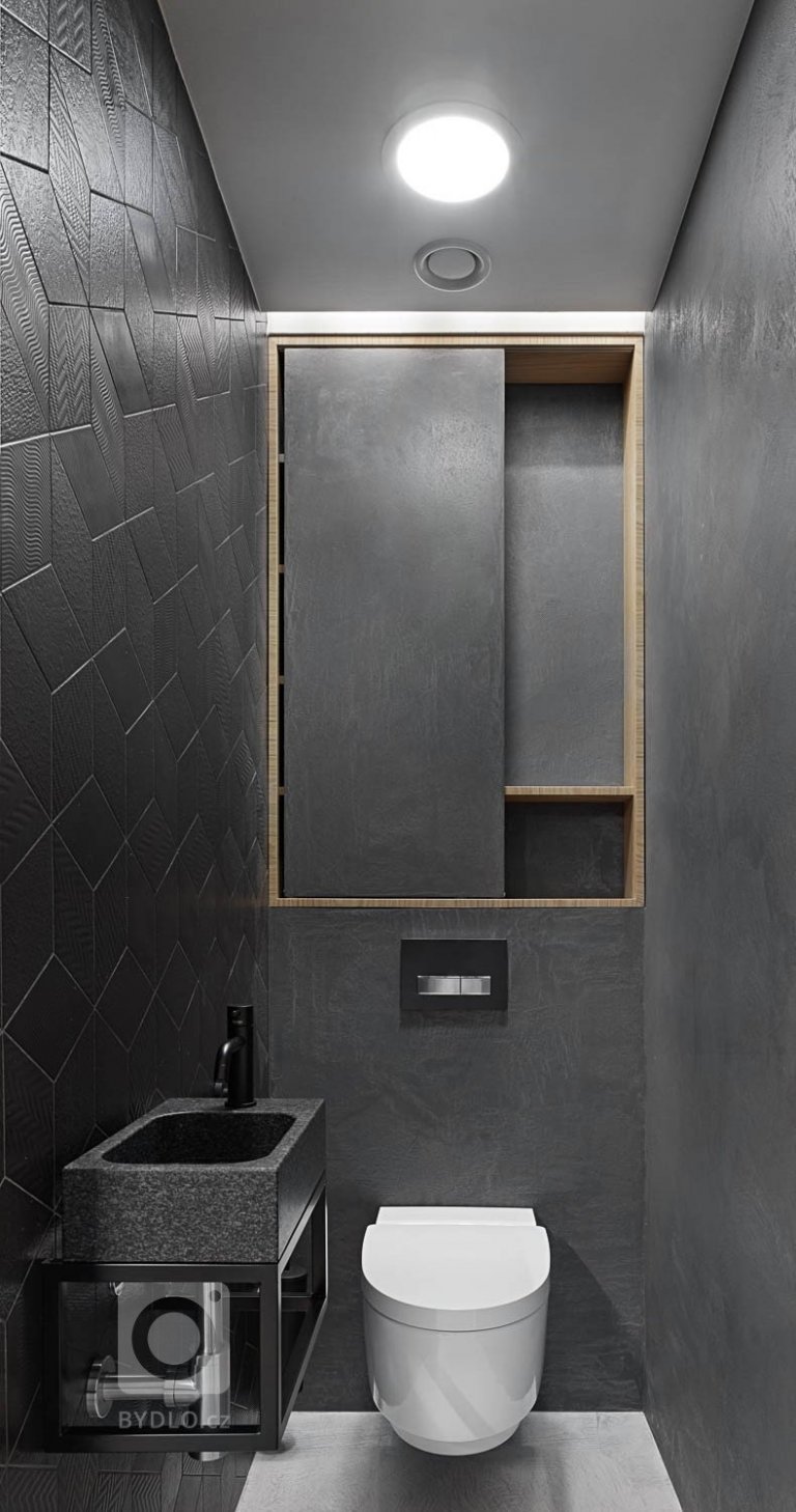 Na záchod byla navržena elektrická integrovaná bidetová sprcha. Dominuje tmavým obkladem a kamenným umyvadlem.