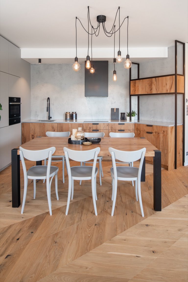 Jídelní stůl pro 6 až 8 osob byl vyroben ve stejném duchu, jako zbytek interiéru, na míru z masivního dubového dřeva a oceli. 