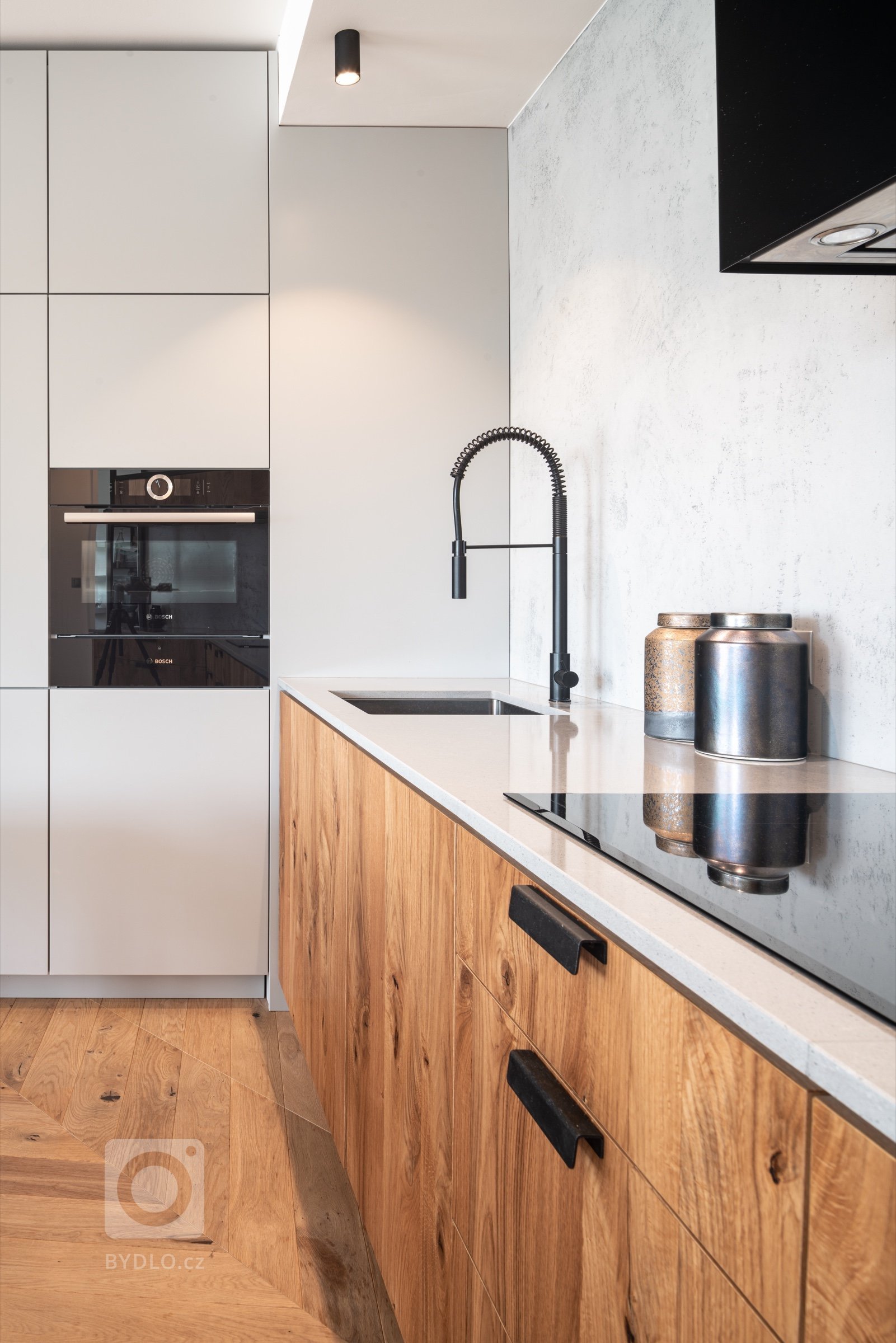 Výrazným prvkem minimalistické kuchyňské linky je netradiční černá kuchyňská baterie.