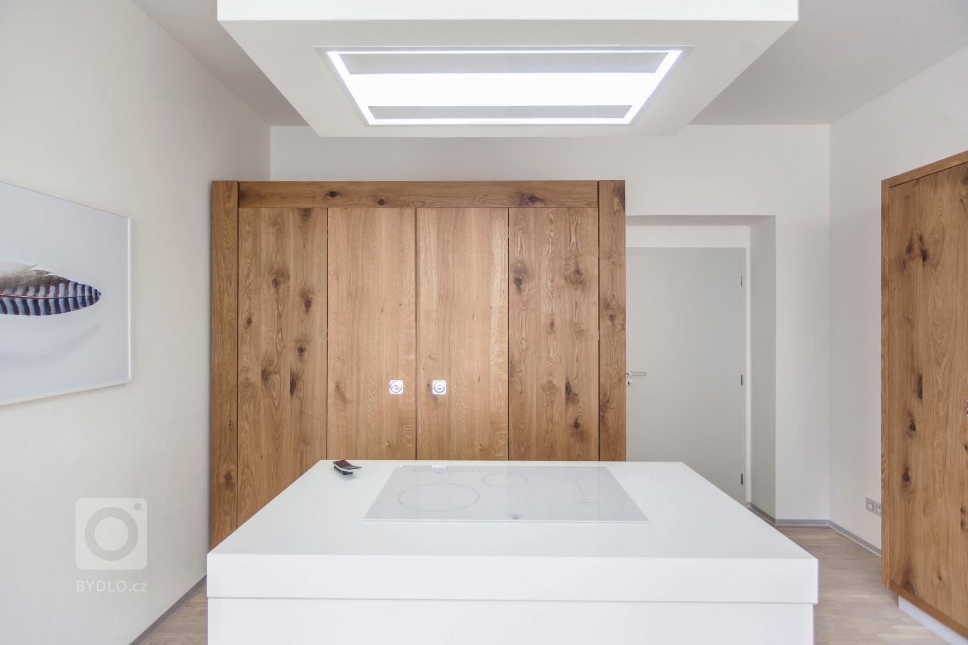 Netradiční řešení skříňové kuchyně. Stroze bílá kuchyň je zasazena do rustikální dubové skříně. Hlavní část kuchyně doplňuje potravinová skříň a ostrůvek s…