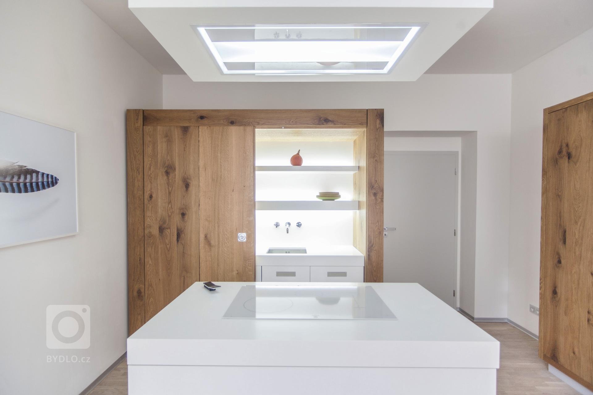 Netradiční řešení skříňové kuchyně. Stroze bílá kuchyň je zasazena do rustikální dubové skříně. Hlavní část kuchyně doplňuje potravinová skříň a ostrůvek s…