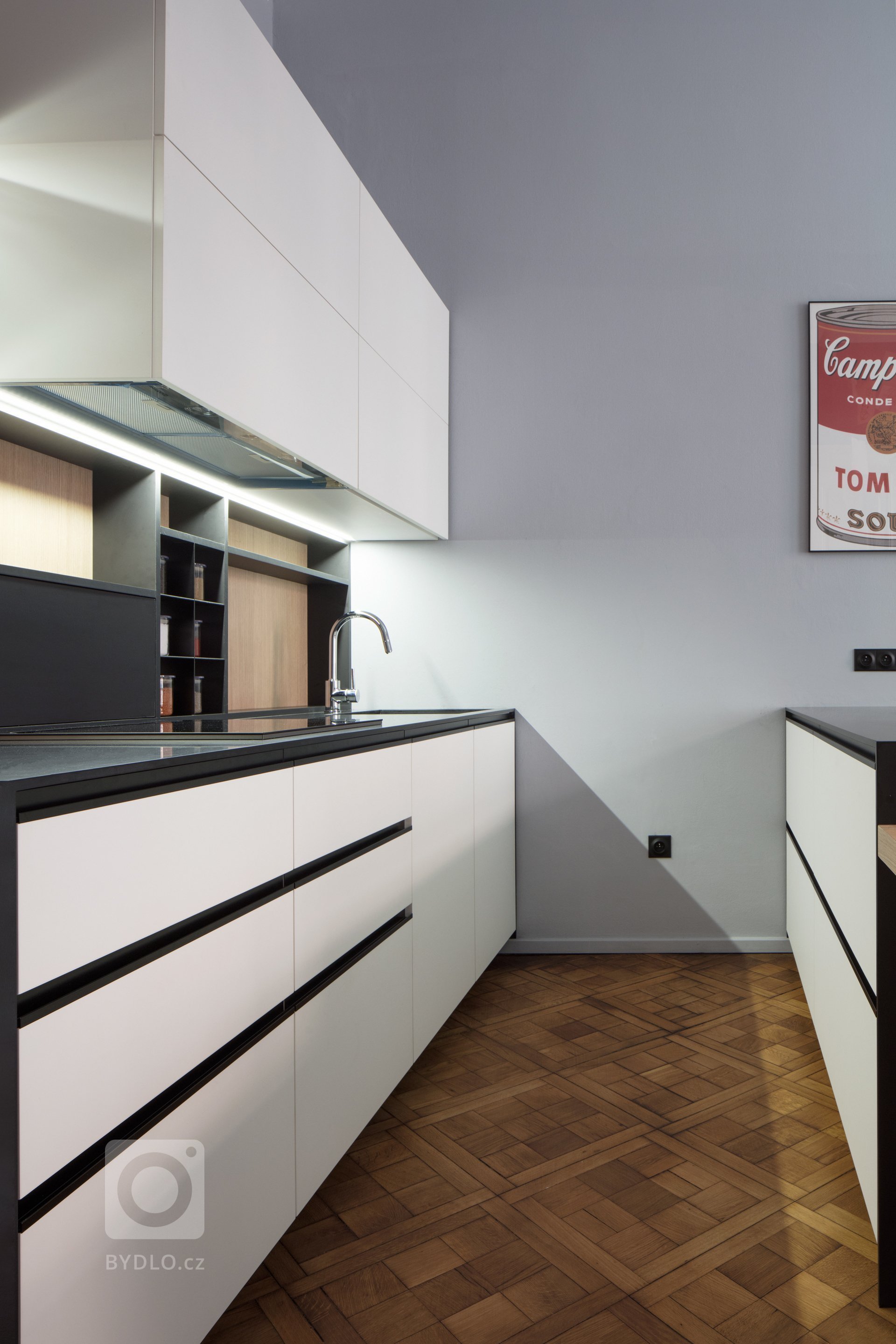 Moderní kuchyně citlivě korespondující s bytem v historickém domě v Královských Vinohradech. Použity byly materiály jako: černý Corian, bělená dubová dýha.…