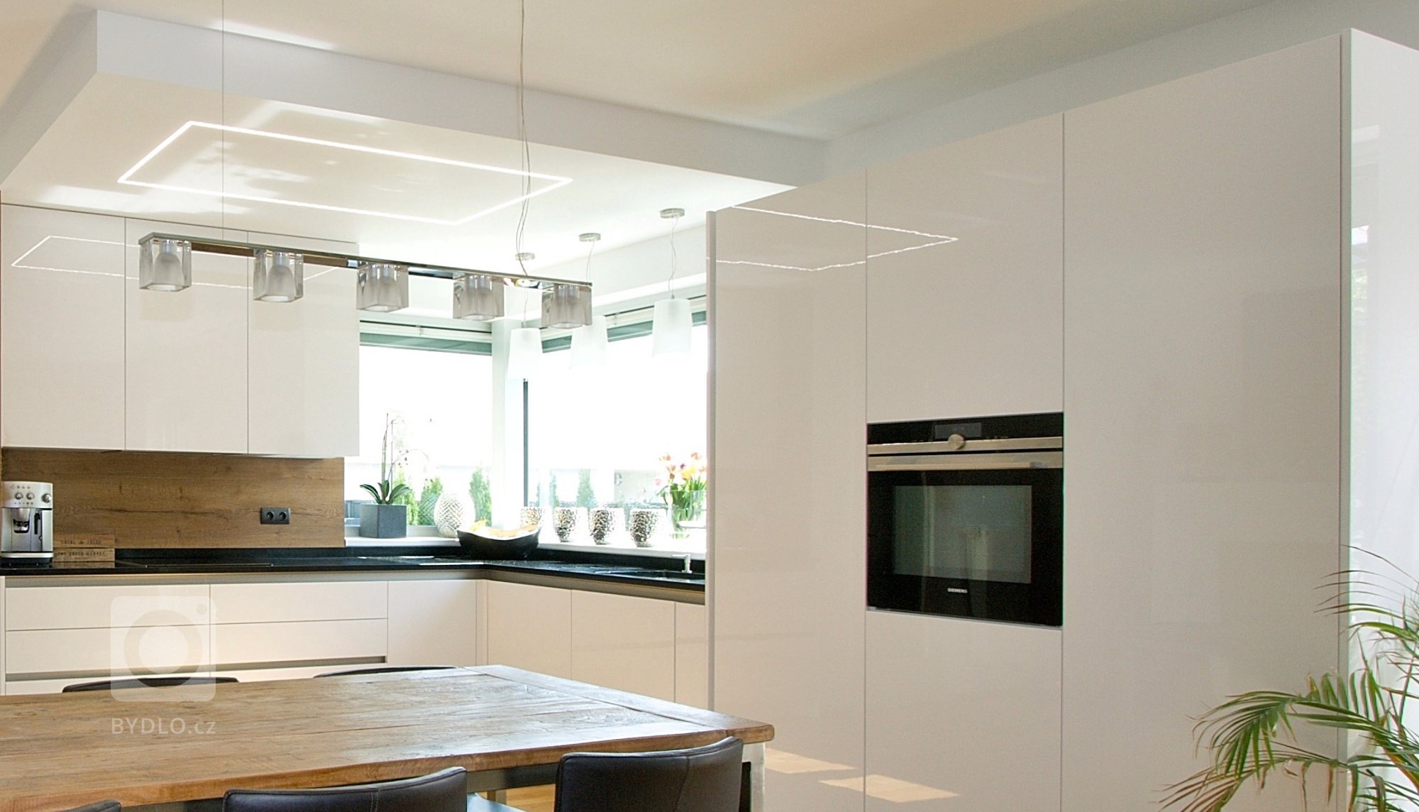 Kuchyň BEECK KÜCHEN, rodinný dům. Provedení lesklý lak s PP hranami Colora. Pracovní deska je Technistone Gobi Black, jako obklad je použito lamino Halifax,…