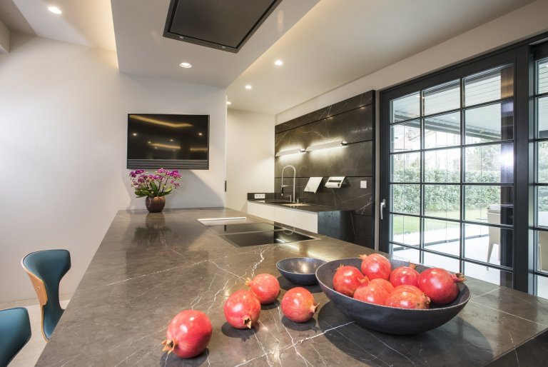 Kuchyň EGGERSMANN UNIQUE, rodinný dům. Provedení je masivní kámen Graphit Brown Leather na ostrůvku v&nbsp;kombinaci s Paso supermatt lotus white a broušeným…