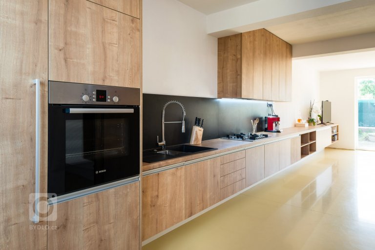 Moderná a zároveň funkčná kuchynská linka, ktorá plynulo prechádza do obývacej zostavy pozdĺž celého interiéru.
