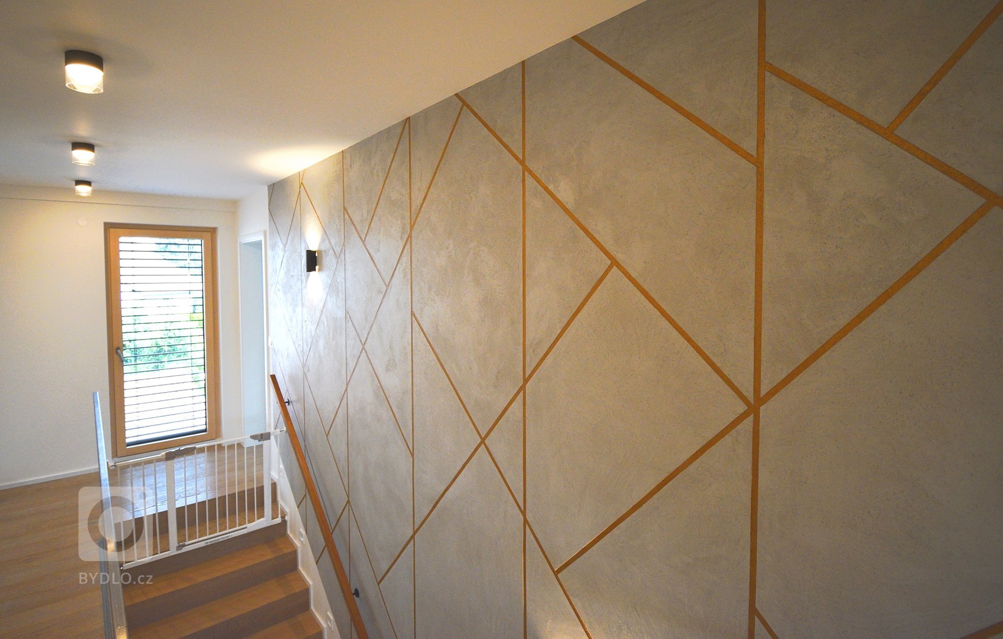 Realizace dekorativních aplikací v geometrickém designu. Reliéfní betonová stěrka se spárou probarvenou v měděnné metaléze, dále dekorativní šablonová malba a…