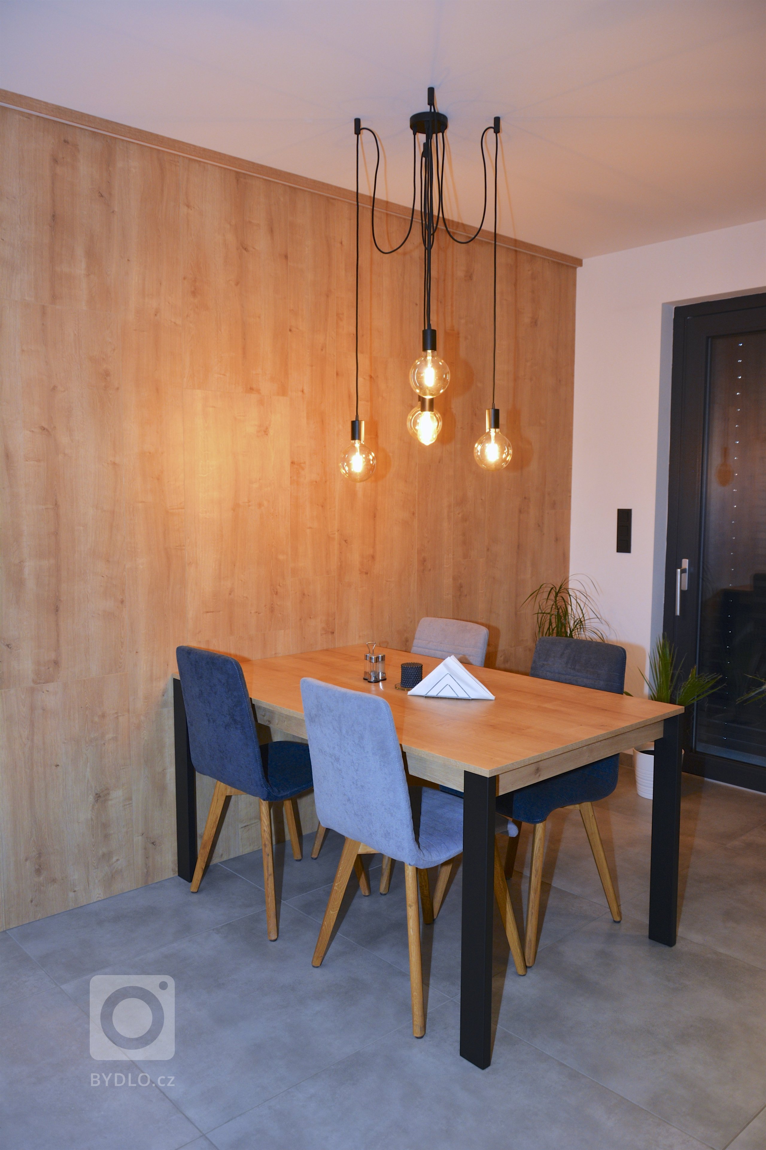 Dnes tu máme praktický interiér. Na kuchyni, jsme použili lamino v dekoru betonu a teplého dubu. Kuchyň plynule navazuje na podsvícené obložení jídelny, ve…