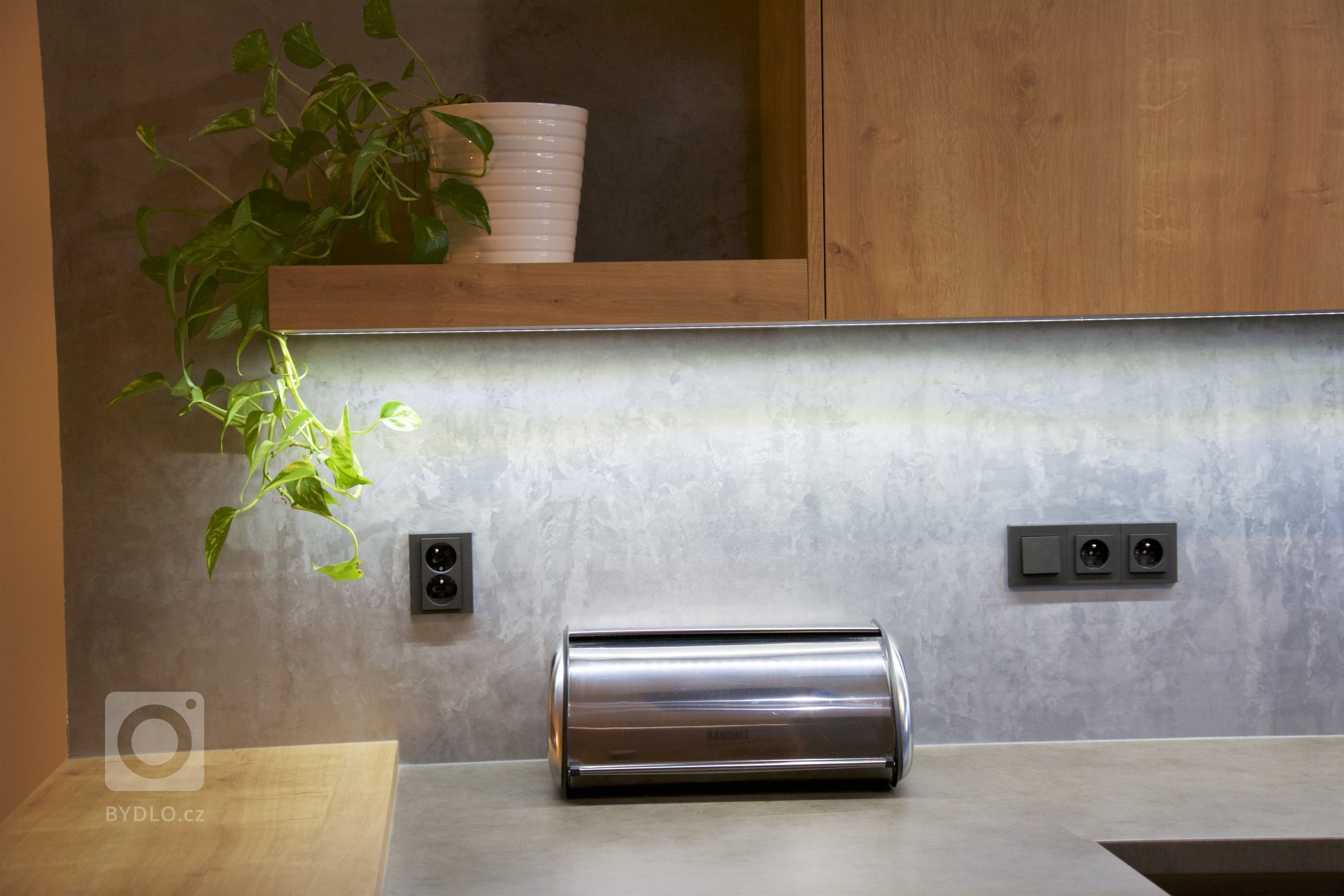 Dnes tu máme praktický interiér. Na kuchyni, jsme použili lamino v dekoru betonu a teplého dubu. Kuchyň plynule navazuje na podsvícené obložení jídelny, ve…