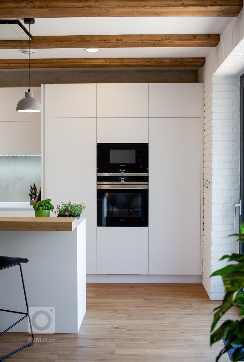 Interiér v minimalistickém stylu, který je laděn do čisté bílé matné doplněné dřevem, trámy a vhodnými doplňky. Interiér je jednoduchý, útulný a svěží.
