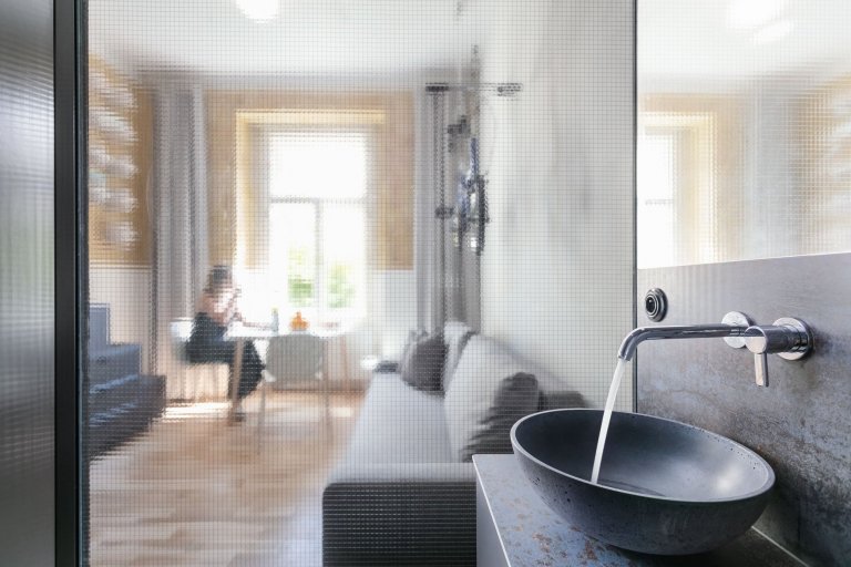 Do vinohradského dvacetimetráku se schoulil černý drak. Po jeho hřbetu je možné vyšplhat do spacího patra. Vnitro obludy skrývá malou koupelnu zářící skrze…