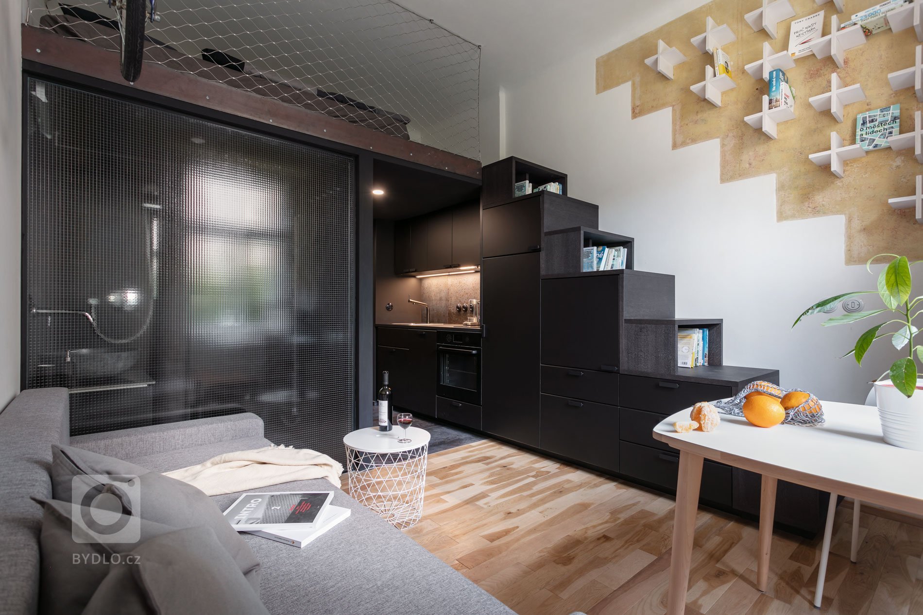 Do vinohradského dvacetimetráku se schoulil černý drak. Po jeho hřbetu je možné vyšplhat do spacího patra. Vnitro obludy skrývá malou koupelnu zářící skrze…