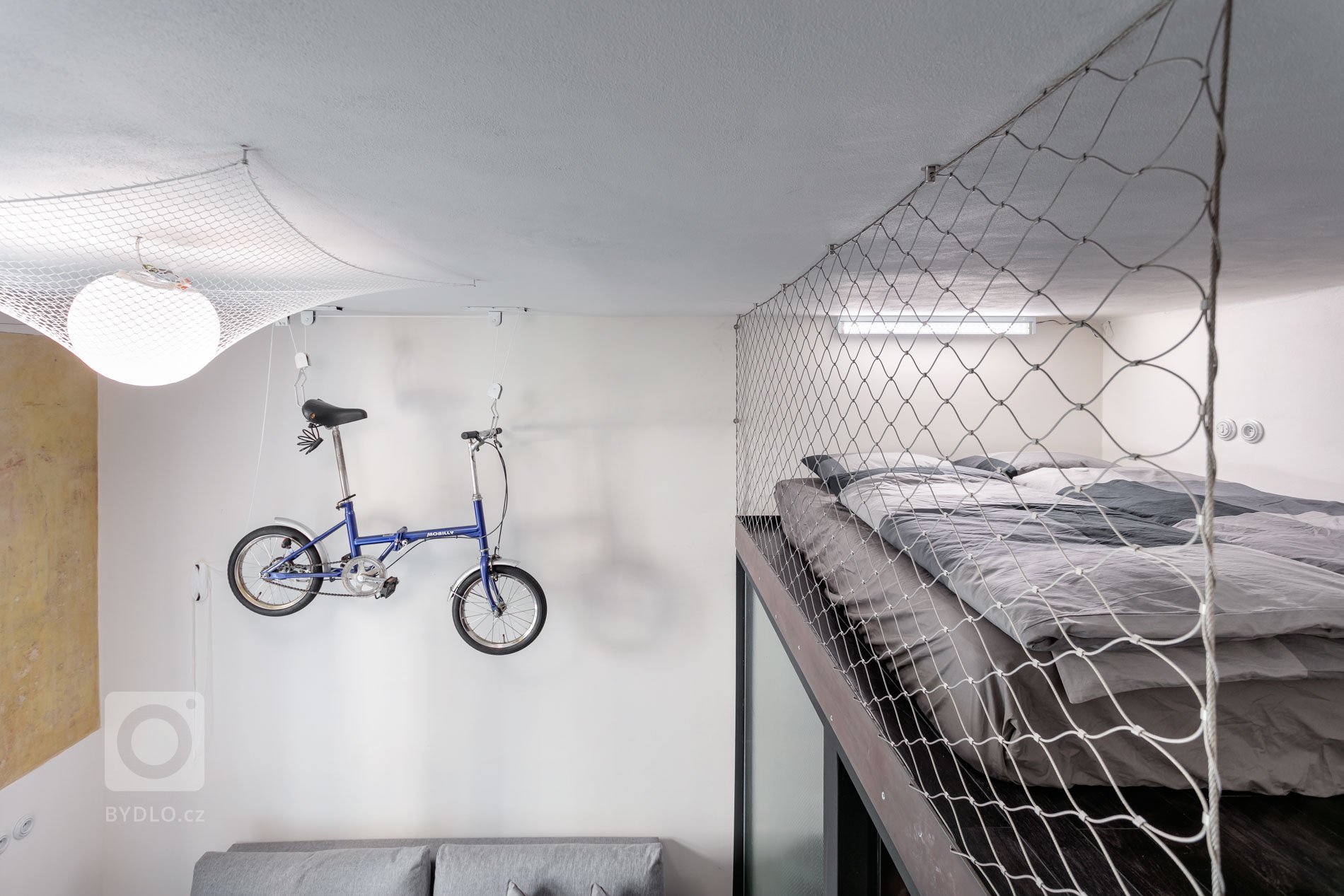 Do vinohradského dvacetimetráku se schoulil černý drak. Po jeho hřbetu je možné vyšplhat do spacího patra. Vnitro obludy skrývá malou koupelnu zářící skrze…