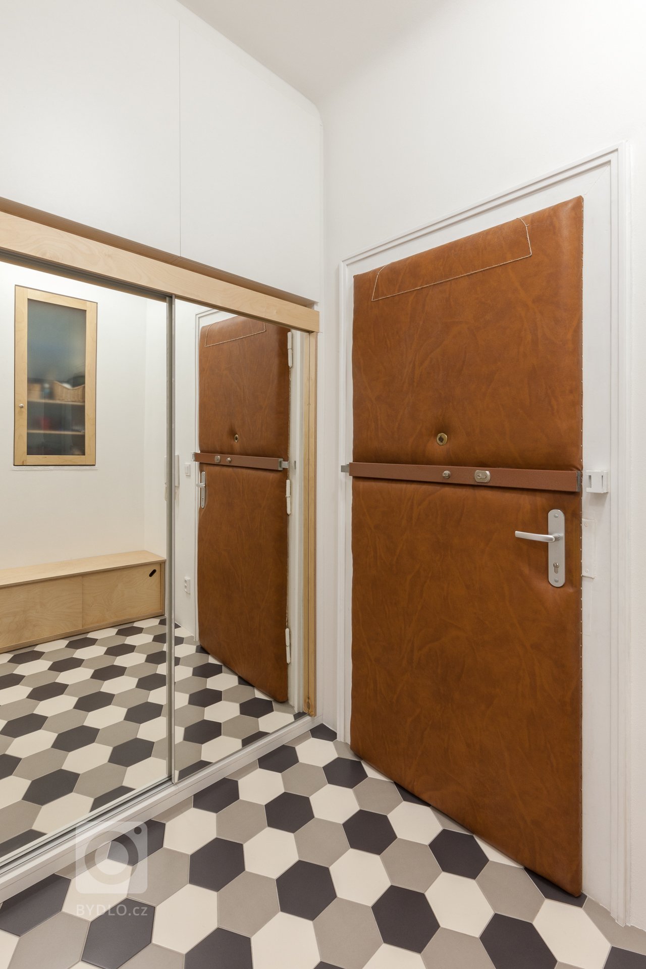 Do vstupní haly byla vestavěna koupelna a šatní skříň sloužící jako technická místnost s pračkou. V předsíni zbyl dostatečný prostor pro botník a věšák. Zrcadlo je umístěné na posuvné dveře "technické místnosti" a mimo praktické účely slouží i k optickému zvětšení prostoru. 