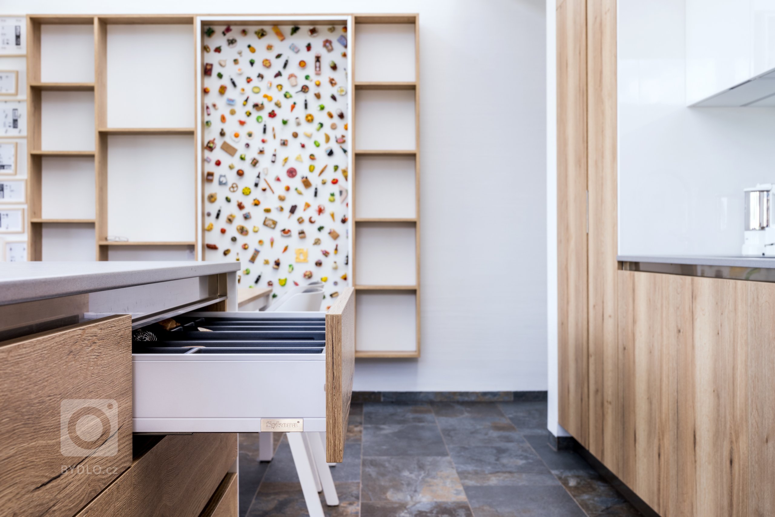 Ostrůvek poskytuje spoustu místa na přípravu jídel: z vnitřní strany jsou navíc zásuvky pro příbory, zatímco na té venkovní se nachází odkládací polička.