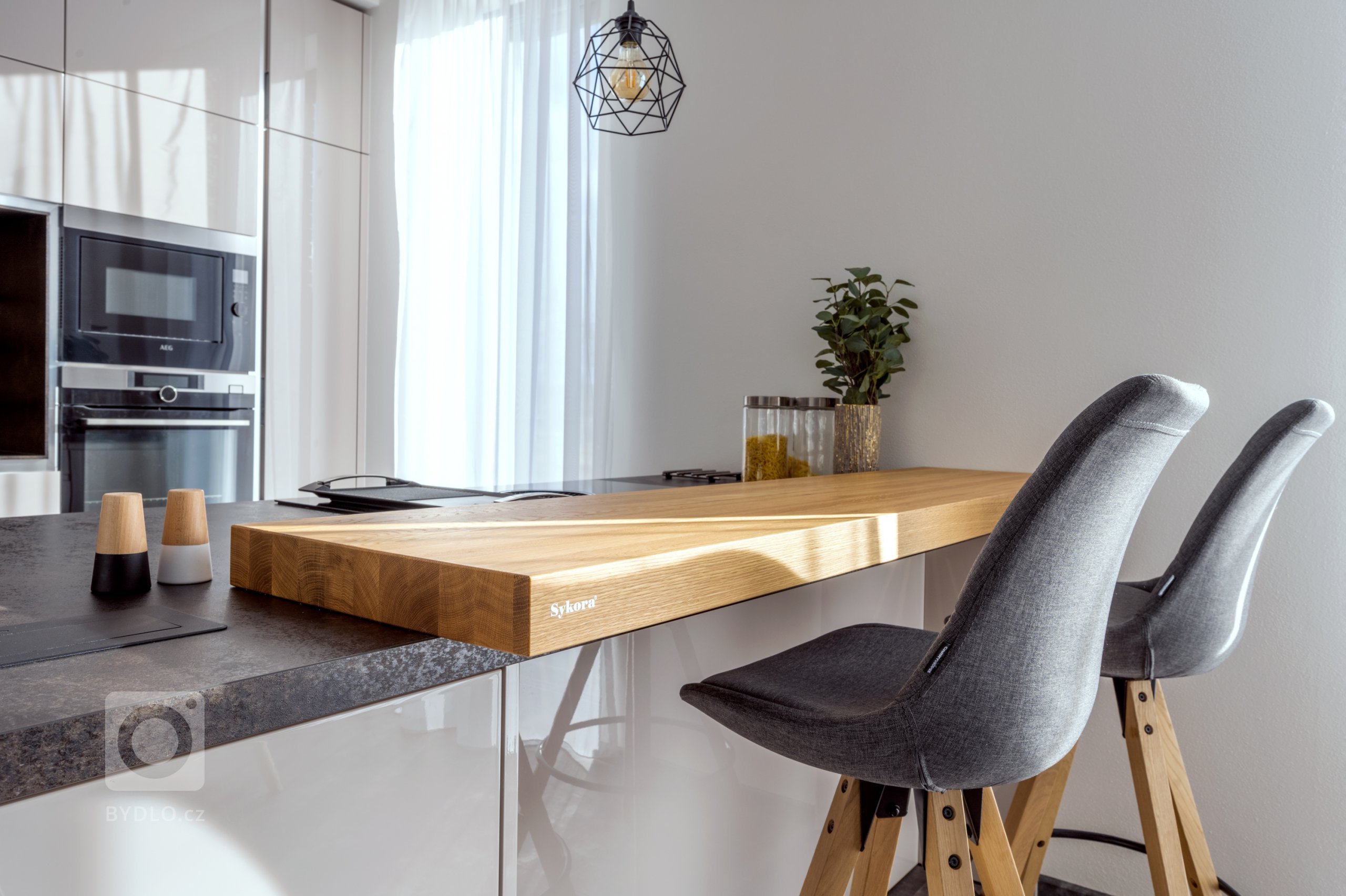 Ostrůvek s prodloužením v podobě barového pultu z masivního dubu. Právě na něm se servírují pohádkové snídaně každý víkend.