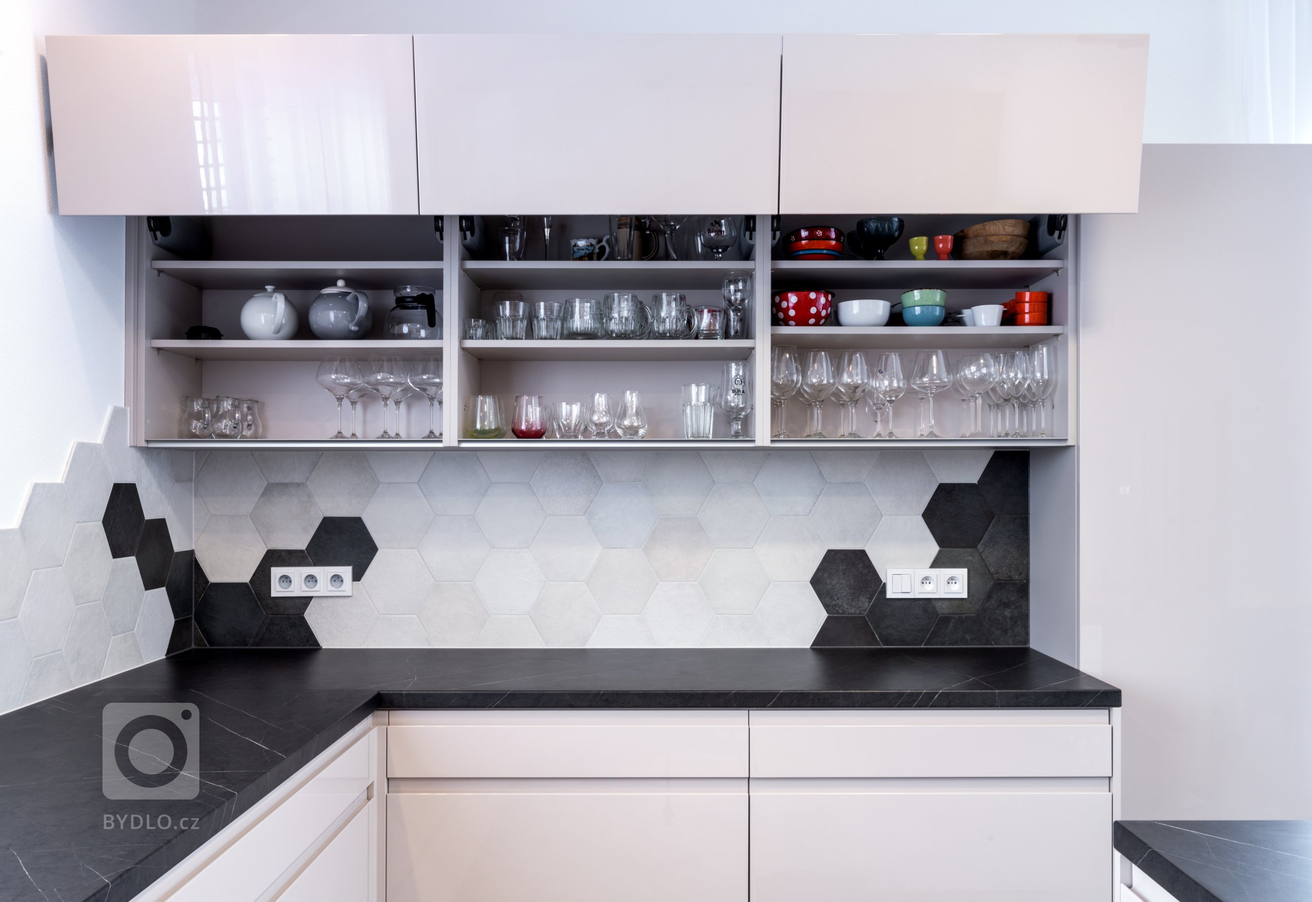 Horní skříňky mají lomené otevírání nahoru, takže dvířka nijak nepřekáží a zároveň zpřístupní kompletní obsah uvnitř. Stačí vysunout krycí plochu nahoru a pak zase komfortně zaklapnout.