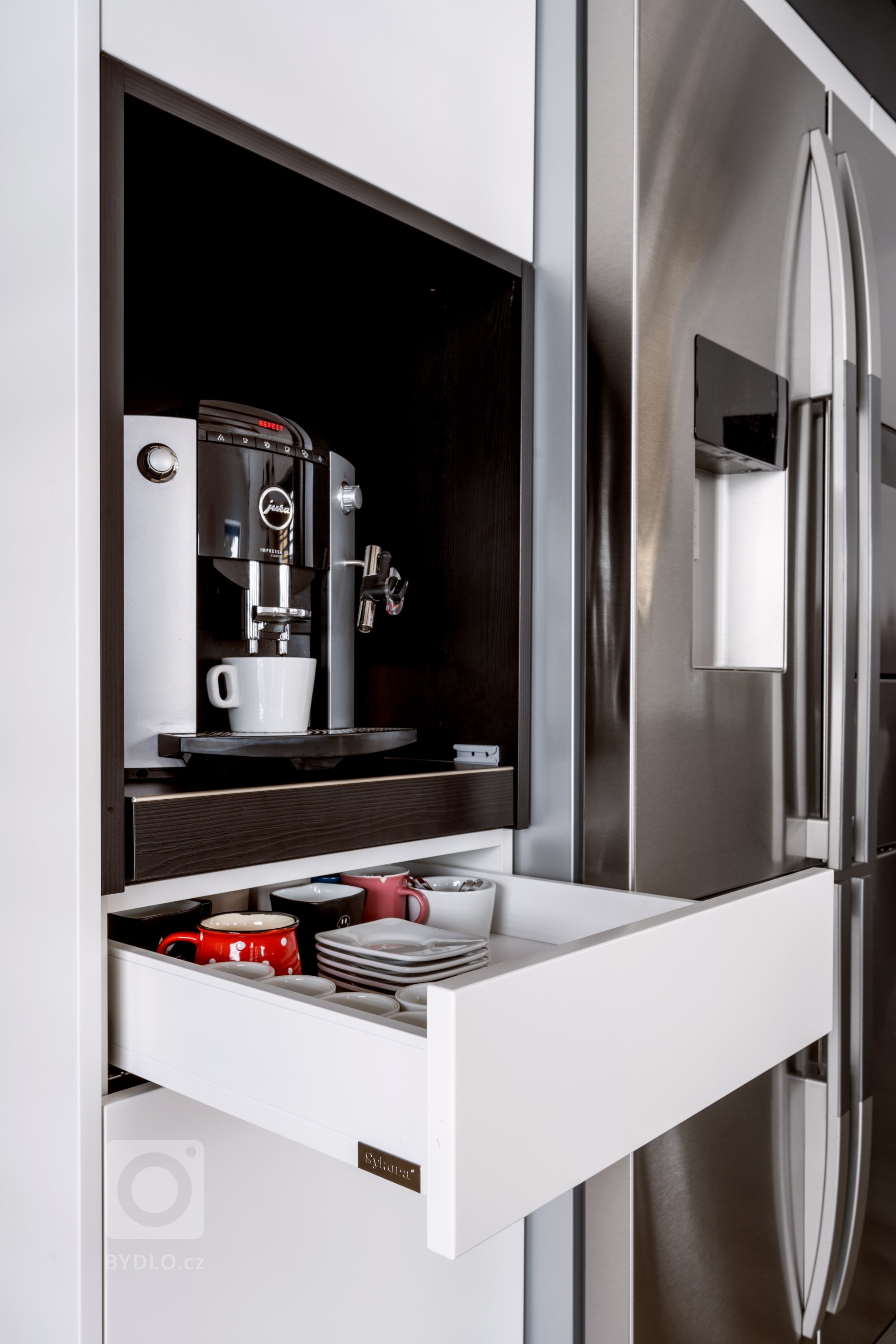 Majitelé milují dobrou kávu a tak v sestavě nemůže chybět kvalitní kávovar. Objevíte ho ve výsuvné nice na levé straně sestavy. Hned pod ním je umístěna elegantní zásuvka na hrníčky