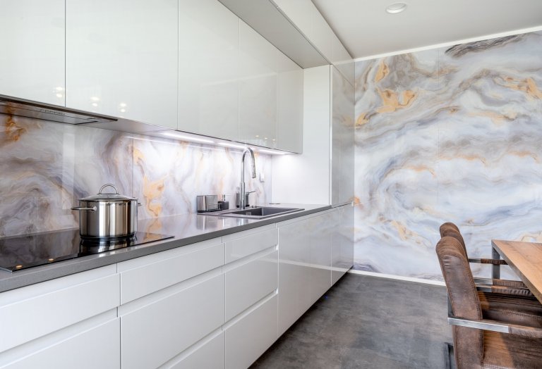 Nejvýraznějšími designovými prvky této kuchyně jsou obkladové zástěny ze skla Onyx. Tvoří boční obložení nad mycí a varnou zónou a pokrývají i celou jednu stěnu místnosti.