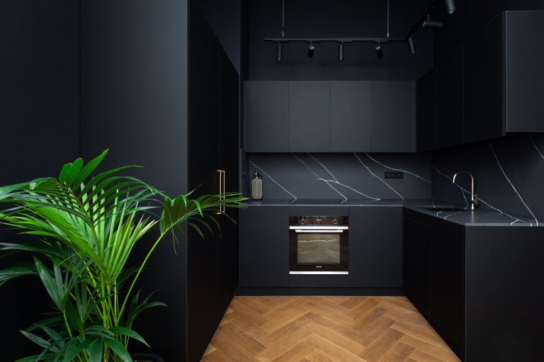 Černá kuchyně na míru s pracovní deskou z černého mramoru s výrazným bílým žilkováním. 