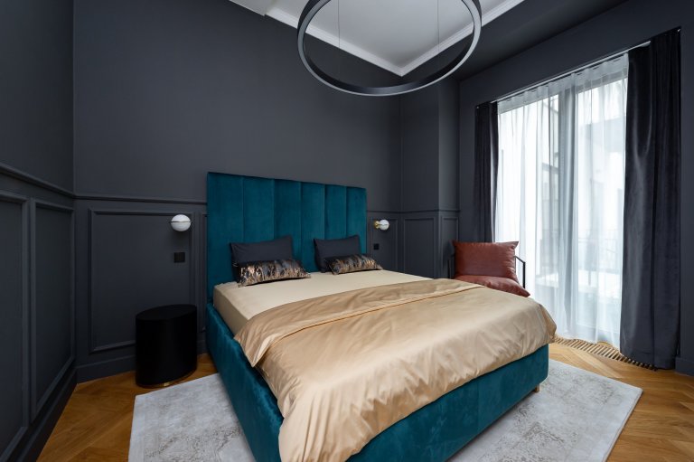 Ložnice s čalouněnou postelí ze zeleného sametu vyrobenou na míru. Atypická výška čela postele je 170 cm. Na stěnách jsou okrasné lišty a celá místnost je vymalována do antracitové barvy. 