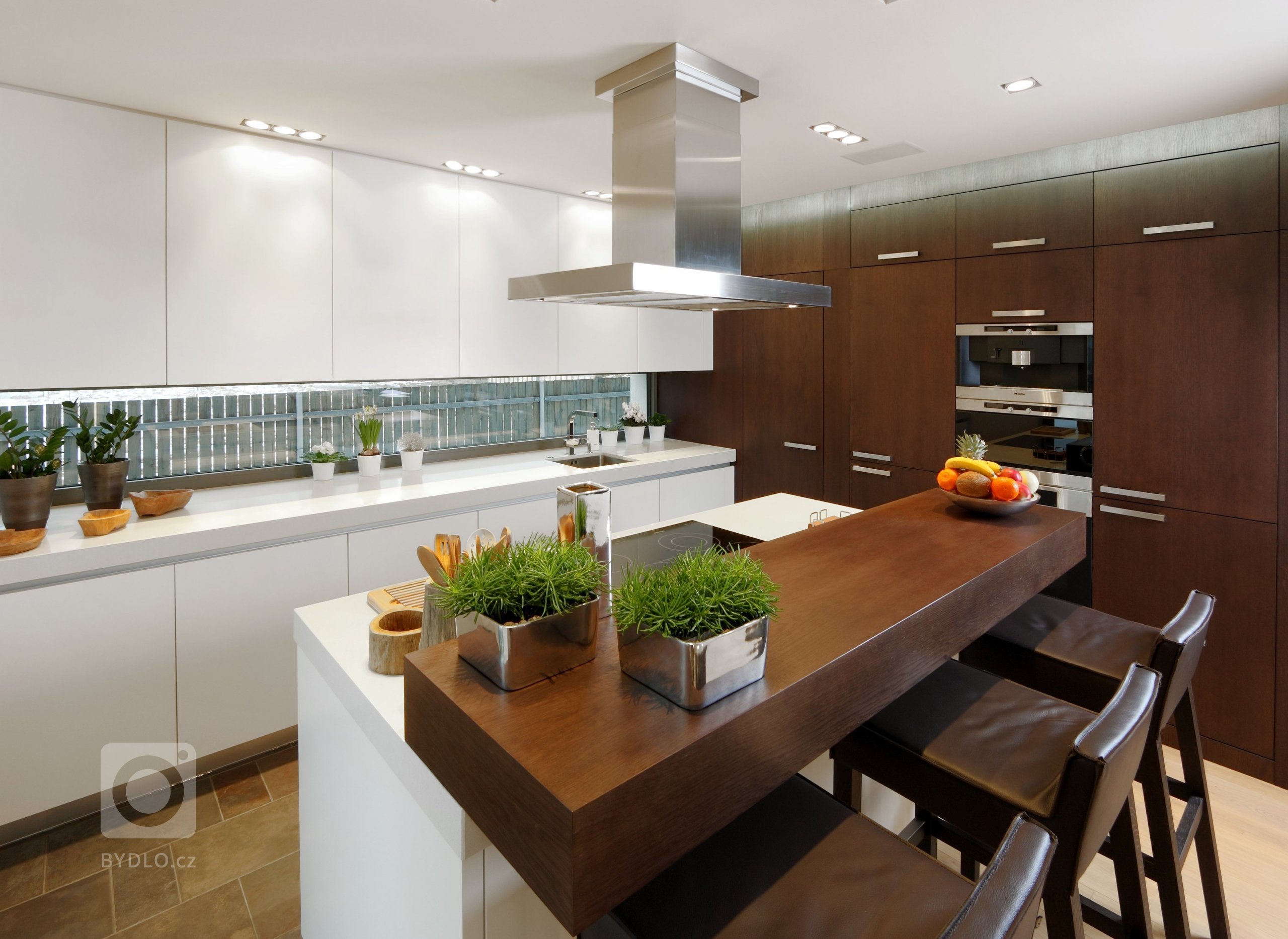 Prostorná a impozantní kuchyň s ostrůvkem, plná odvážných hran a kontrastů. Lakované povrchy střídají tmavou barvu s bílou a podtrhují tak její minimalistický…