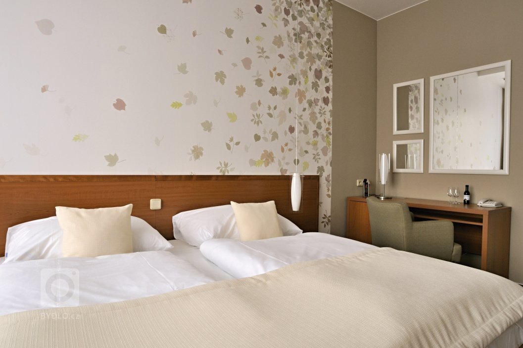 Proměna hotelového pokoje s částečným využitím stávajícího mobiliáře. Barevné ladění&nbsp;v podzimních tónech s odpovídajícím dekorem obrazové tapety přináší…