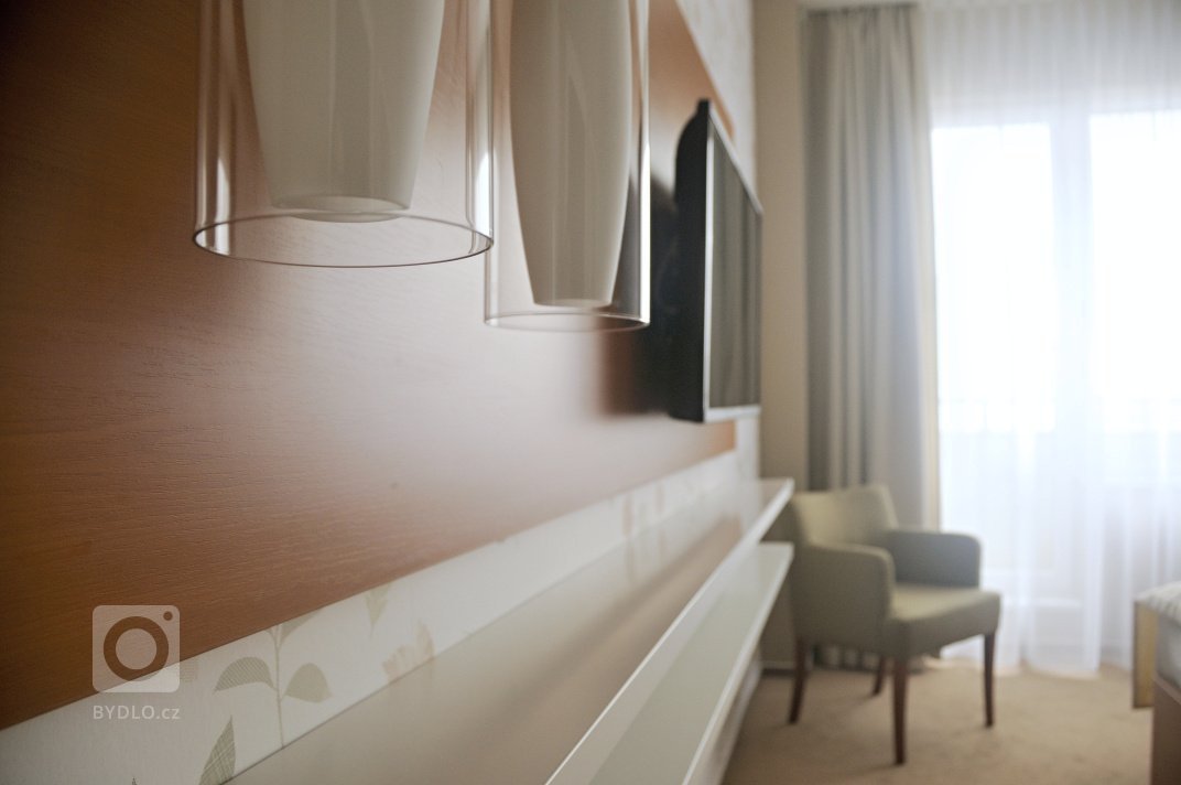 Proměna hotelového pokoje s částečným využitím stávajícího mobiliáře. Barevné ladění&nbsp;v podzimních tónech s odpovídajícím dekorem obrazové tapety přináší…