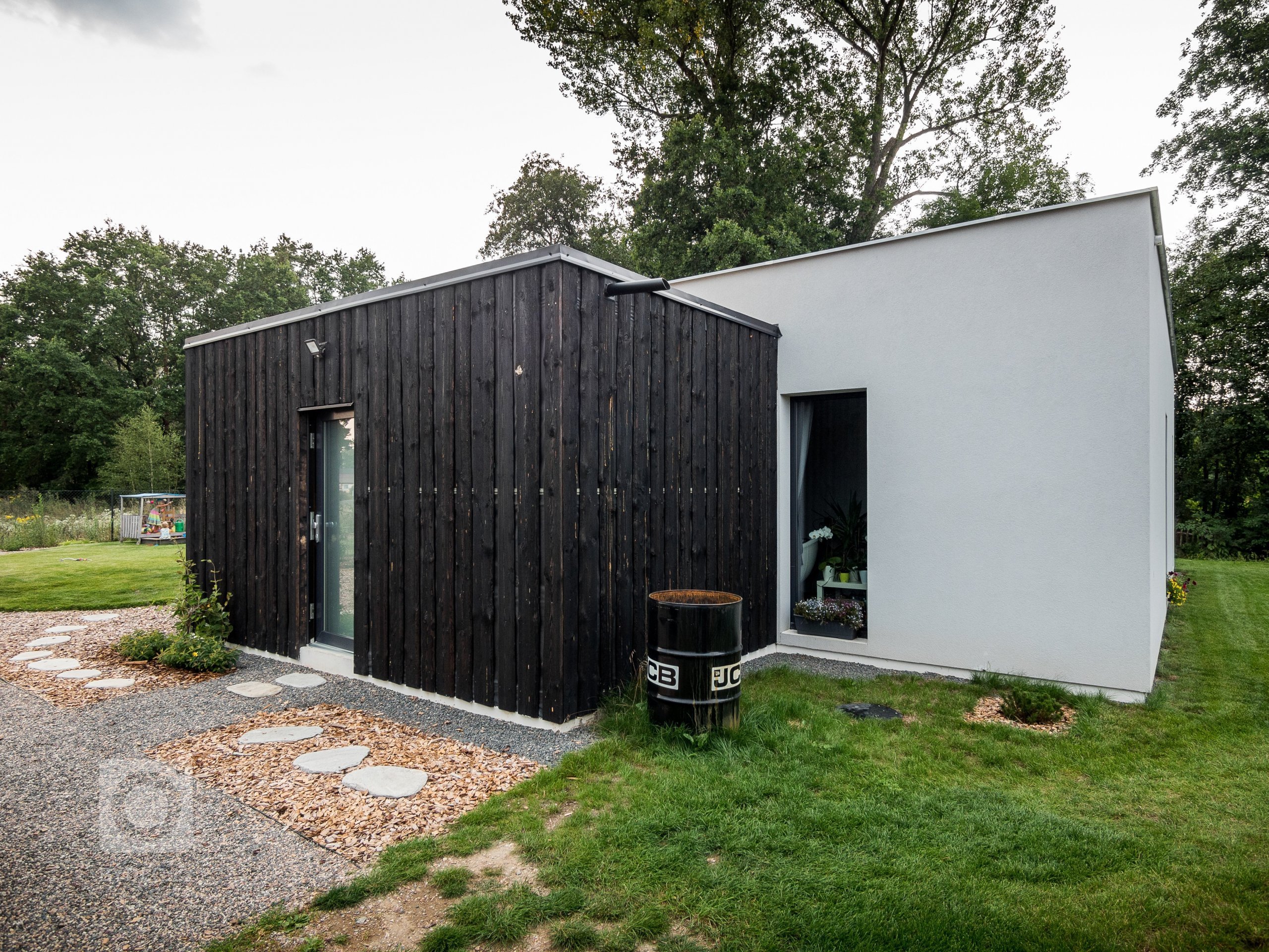 Základní hmotu domu ZEN HOME doplňuje přístavba z černých nesámovaných prken.