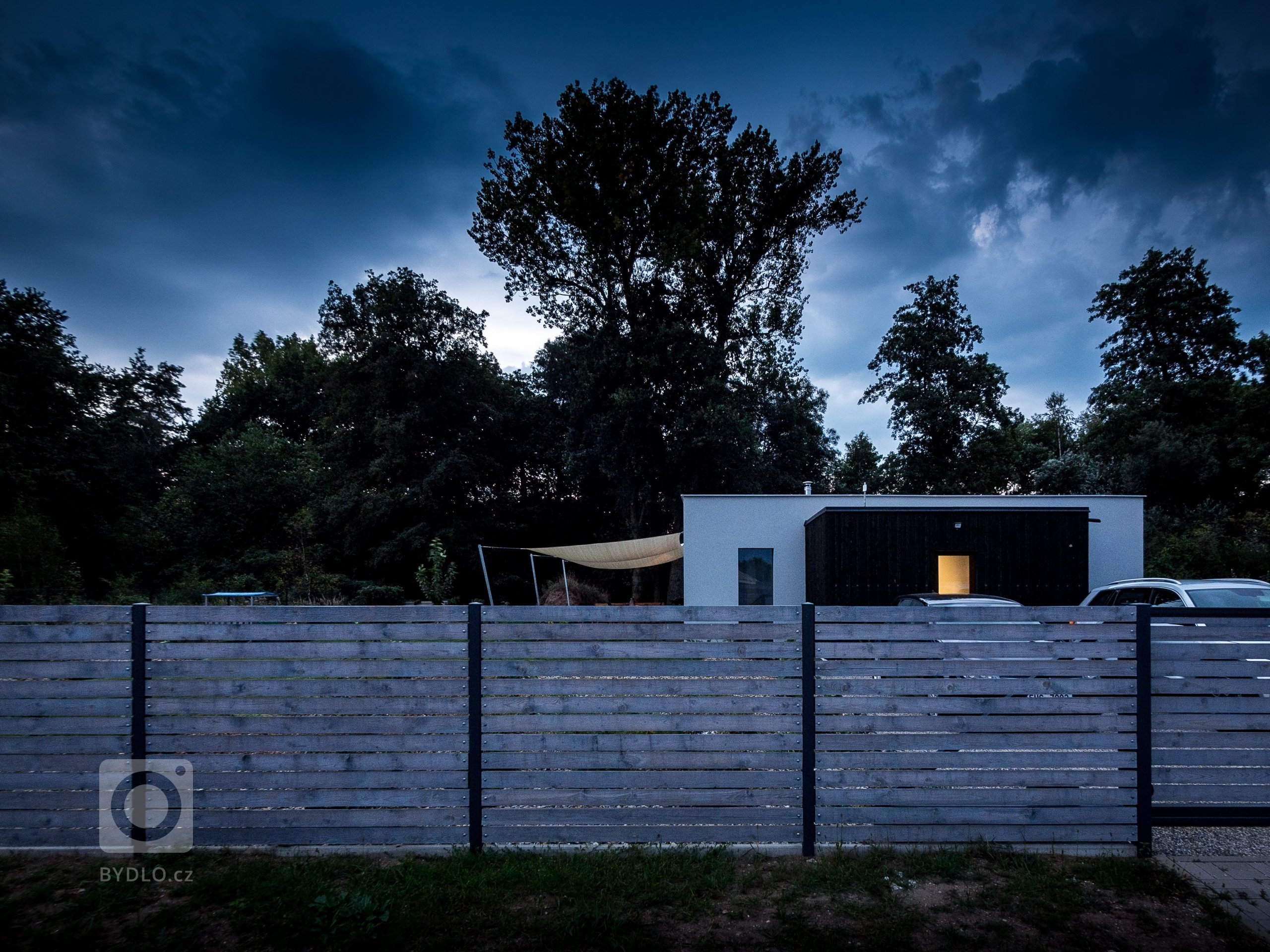 Základní hmotou tohoto ZEN HOME je obyčejný bílý kvádr. Přístavba z černého dřeva, dřevěný plot a stínící plachty přidají dostatek zábavných prvků.